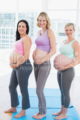 Smiling pregnant women standing in a row