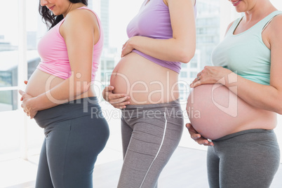 Pregnant women standing in a row looking at bumps