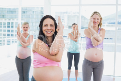 Happy pregnant women in yoga class standing in eagle pose