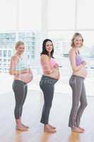 Happy pregnant women standing in a line smiling at camera