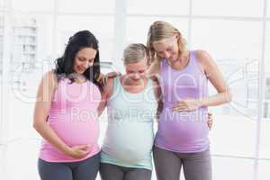 Pregnant women standing smiling at bumps