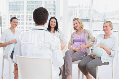 Smiling pregnant women listening to doctor at antenatal class