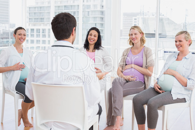 Happy pregnant women listening to doctor at antenatal class