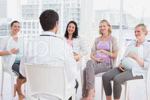 Happy pregnant women listening to doctor at antenatal class