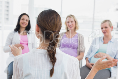 Happy pregnant women listening to gesturing doctor at antenatal