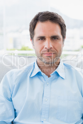 Serious handsome man sitting on the couch looking at camera