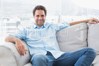 Happy handsome man relaxing on the couch looking at camera