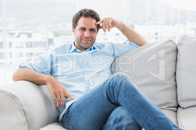 Smiling handsome man relaxing on the couch looking at camera