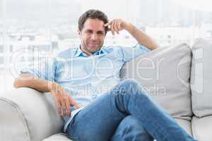 Smiling handsome man relaxing on the couch looking at camera