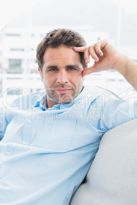 Serious handsome man relaxing on the couch looking at camera