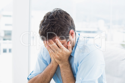 Man with head in hands sitting on the couch