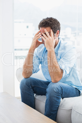 Man with headache sitting on the couch