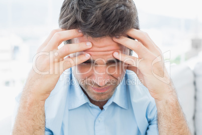 Attractive man sitting on the couch with headache
