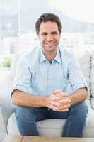 Attractive man sitting on the couch smiling at camera