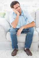 Unhappy man sitting on the couch looking away