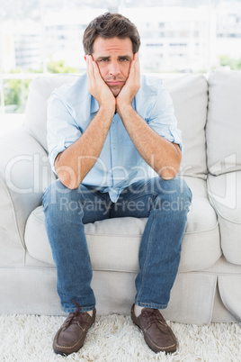 Upset man sitting on the couch looking at camera