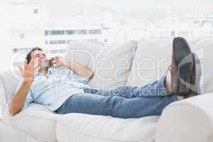 Smiling man lying on the couch talking on the phone