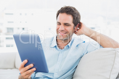 Handsome man sitting on the sofa using his tablet