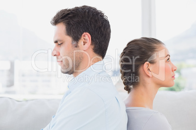 Unhappy couple sitting back to back on the couch