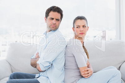 Angry couple sitting back to back on the couch