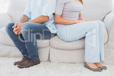 Couple sitting back to back on the couch