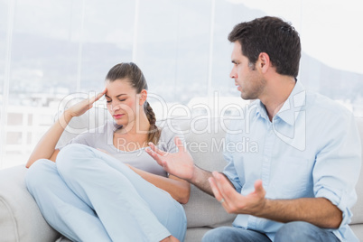 Man pleading with his upset partner on the couch