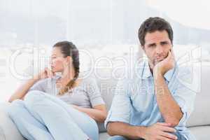 Man looking at camera with upset girlfriend on the couch