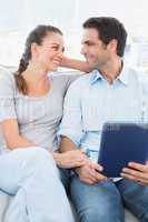 Cute couple sitting on the couch using tablet pc