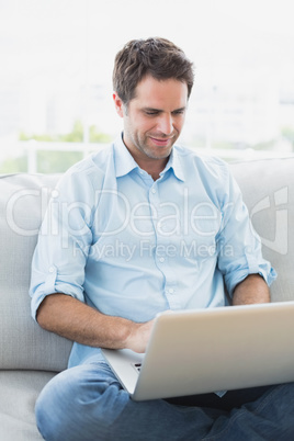 Content man using laptop sitting on sofa