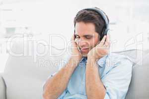 Handsome man sitting on sofa listening to music