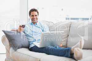 Smiling handsome man relaxing on sofa with glass of red wine usi