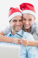 Happy couple in santa hats shopping online
