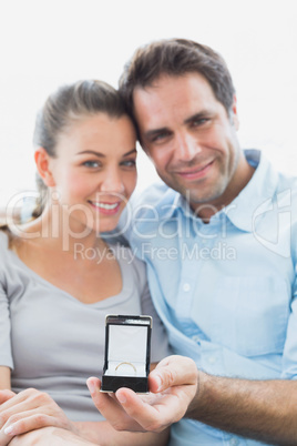 Cheerful young couple getting engaged on the sofa