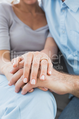 Couple showing wedding ring on womans finger on the couch