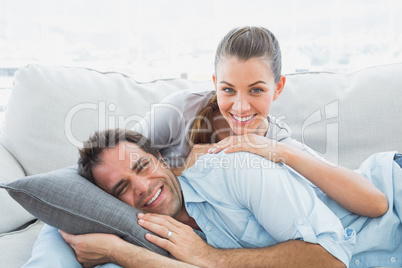 Happy couple relaxing on their sofa smiling at camera