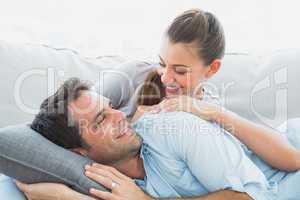 Cheerful couple relaxing on their sofa smiling at each other