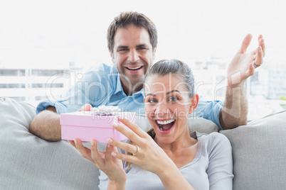 Man surprising his delighted girlfriend with a pink gift on the