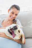 Happy woman cuddling her yellow labrador on the couch