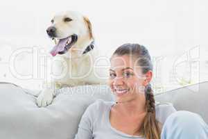 Happy woman posing with her yellow labrador on the couch