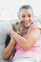 Pretty woman cuddling her yorkshire terrier on the couch
