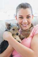Smiling woman cuddling her yorkshire terrier on the couch