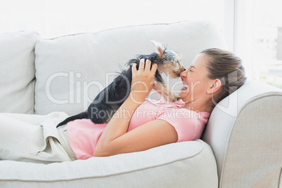 Happy woman playing with her yorkshire terrier on the couch