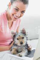 Cheerful woman using laptop with her yorkshire terrier