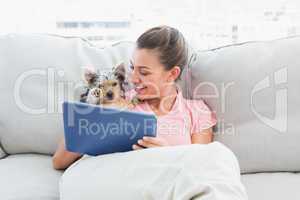 Cheerful woman using tablet with her yorkshire terrier