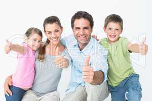 Cute family smiling at camera together showing thumbs up