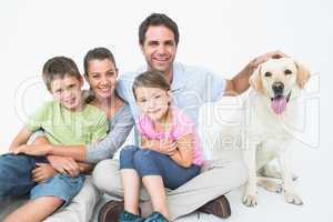 Cute family with pet labrador posing and smiling at camera toget