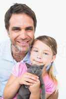 Cute father and daughter with pet kitten smiling at camera toget