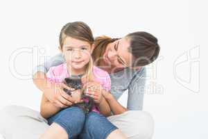Happy daughter and mother sitting with pet kitten together