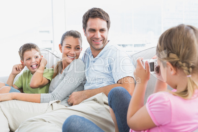 Little girl taking a photo of her family on the couch