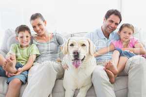 Happy family sitting on couch with their pet labrador